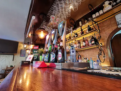 Barra de la sidrería en Móstoles con grifos y botellas, en luz cálida
