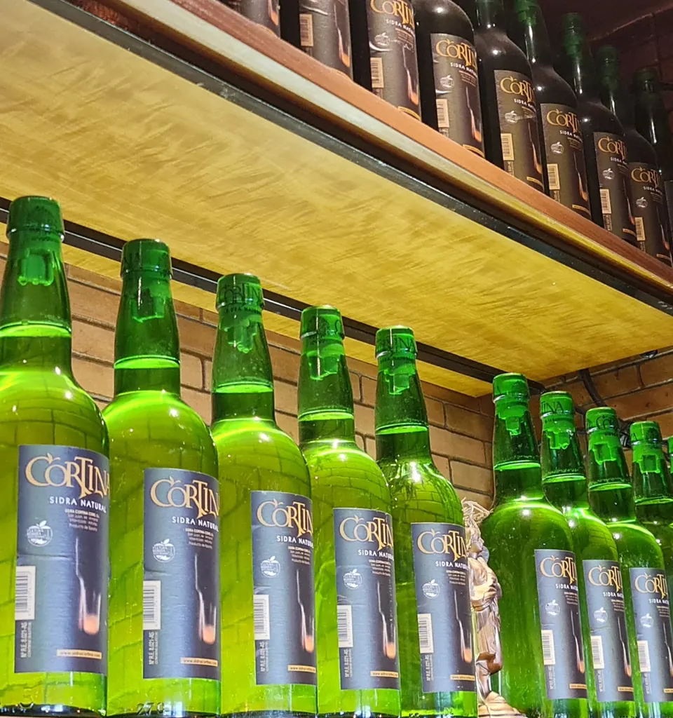 Botellas de sidra natural asturiana Cortina en la estantería de la barra de la sidrería