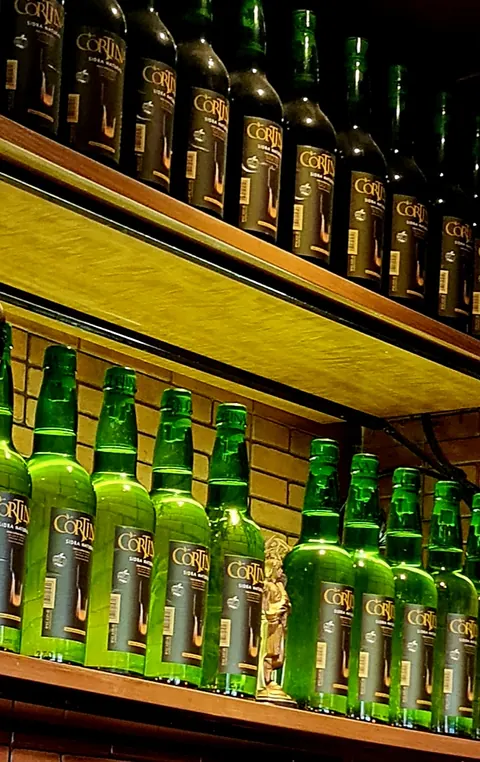 Botellas de sidra natural Cortina en la estantería de Sidrería El Gallu