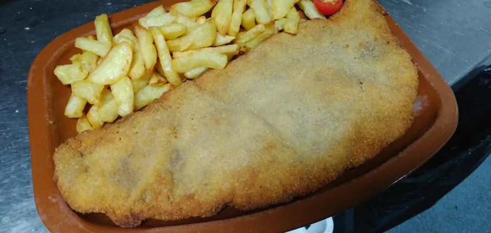 Cachopo asturiano con patatas fritas en fuente de barro, especialidad de la sidrería en Móstoles