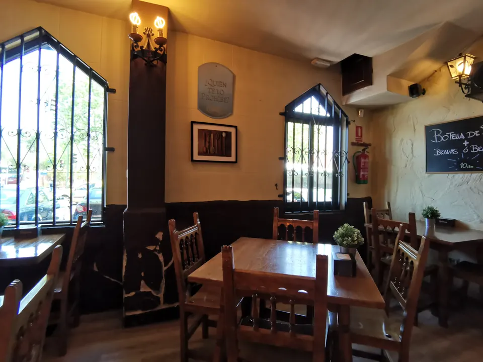 Salón con columna de piedra y mesas de madera de la sidrería asturiana